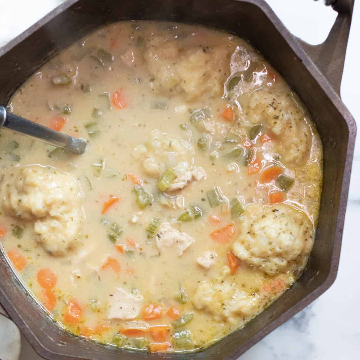 a dutch oven with a creamy chicken and dumplings soup.