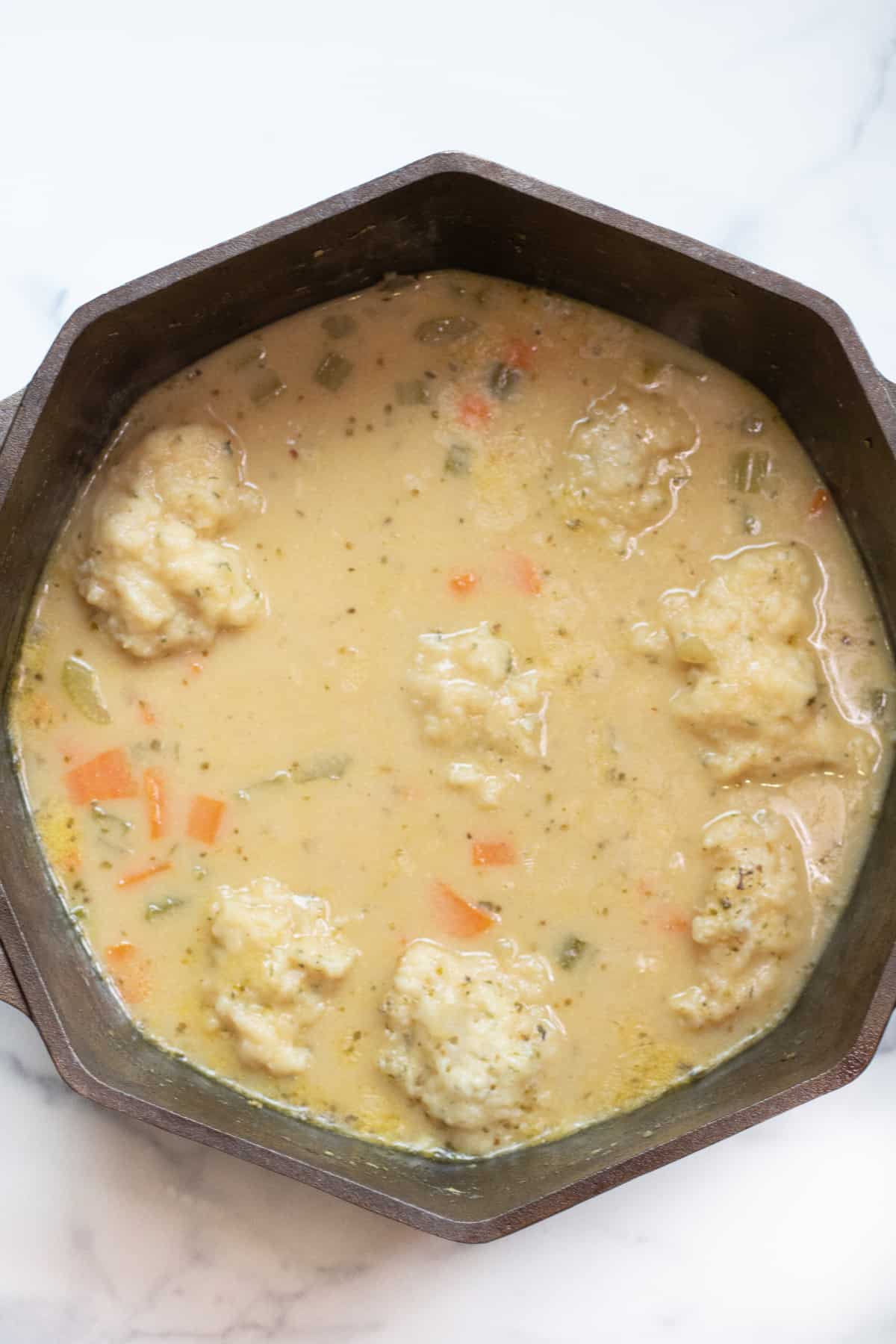 a dutch oven with a creamy chicken and dumplings soup.