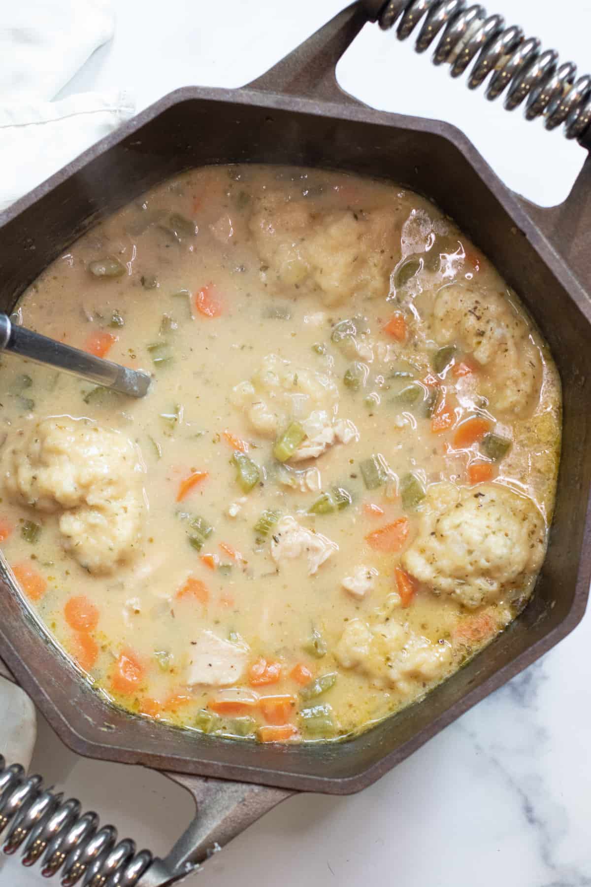 a dutch oven with a creamy chicken and dumplings soup.