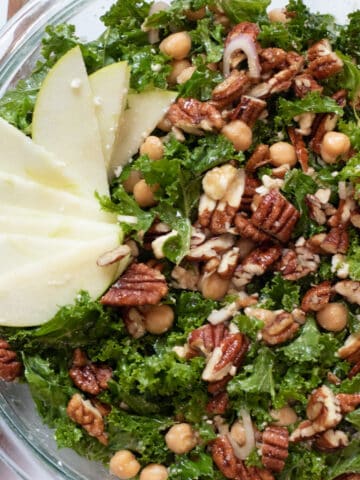 an overhead shot of a kale salad with apples, pecans, and chickpeas.