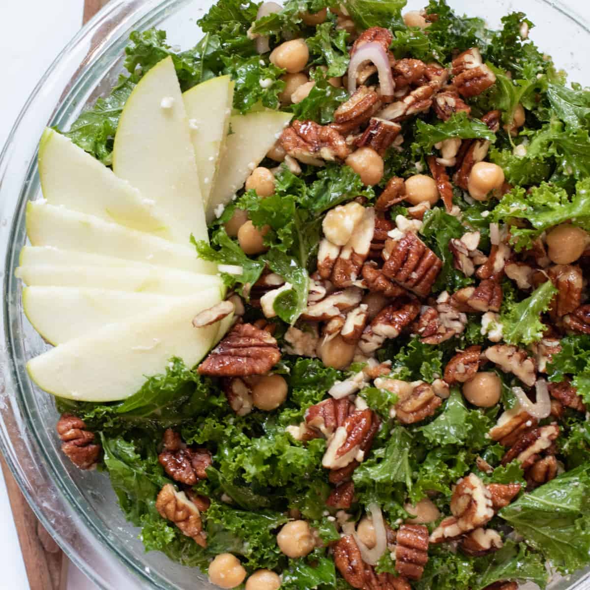 an overhead shot of a kale salad with apples, pecans, and chickpeas.