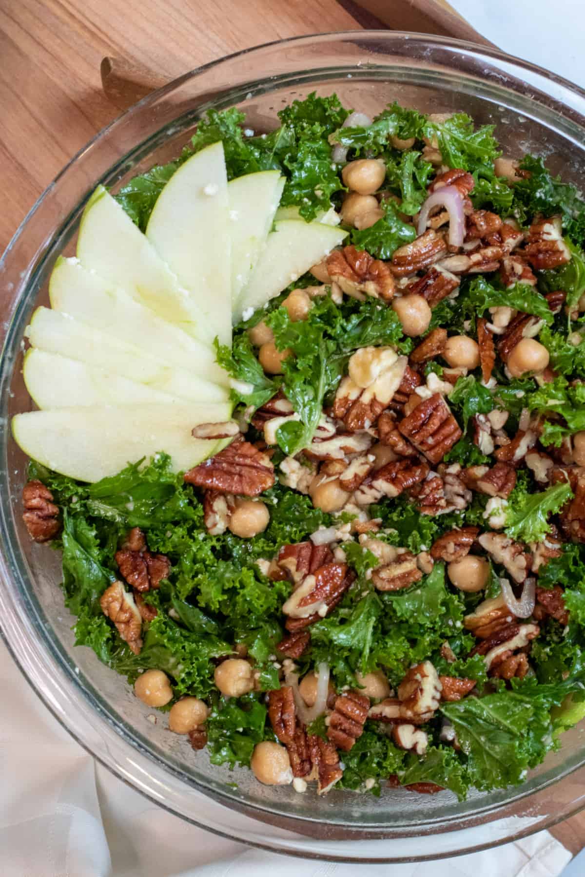 an overhead shot of a kale salad with apples, pecans, and chickpeas.