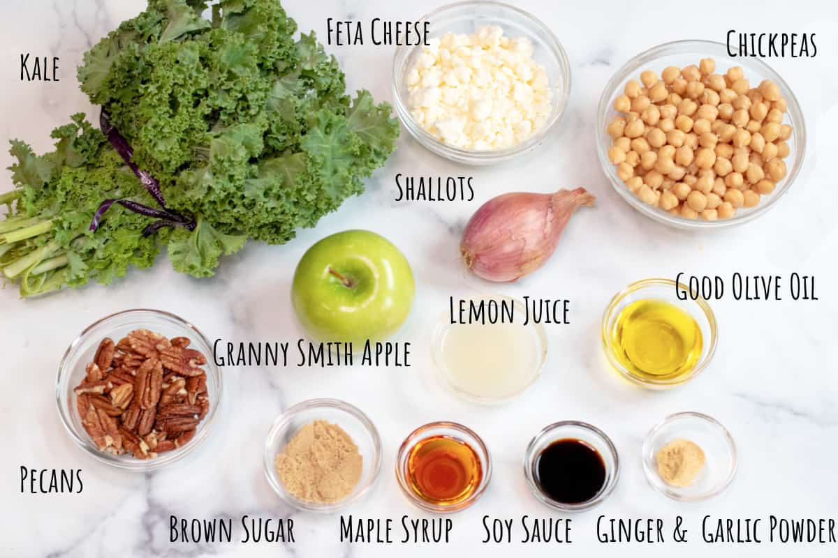 kale, salad, shallot, chickpeas, feta, pecans, apple, olive oil, sugar, and spices in bowls.