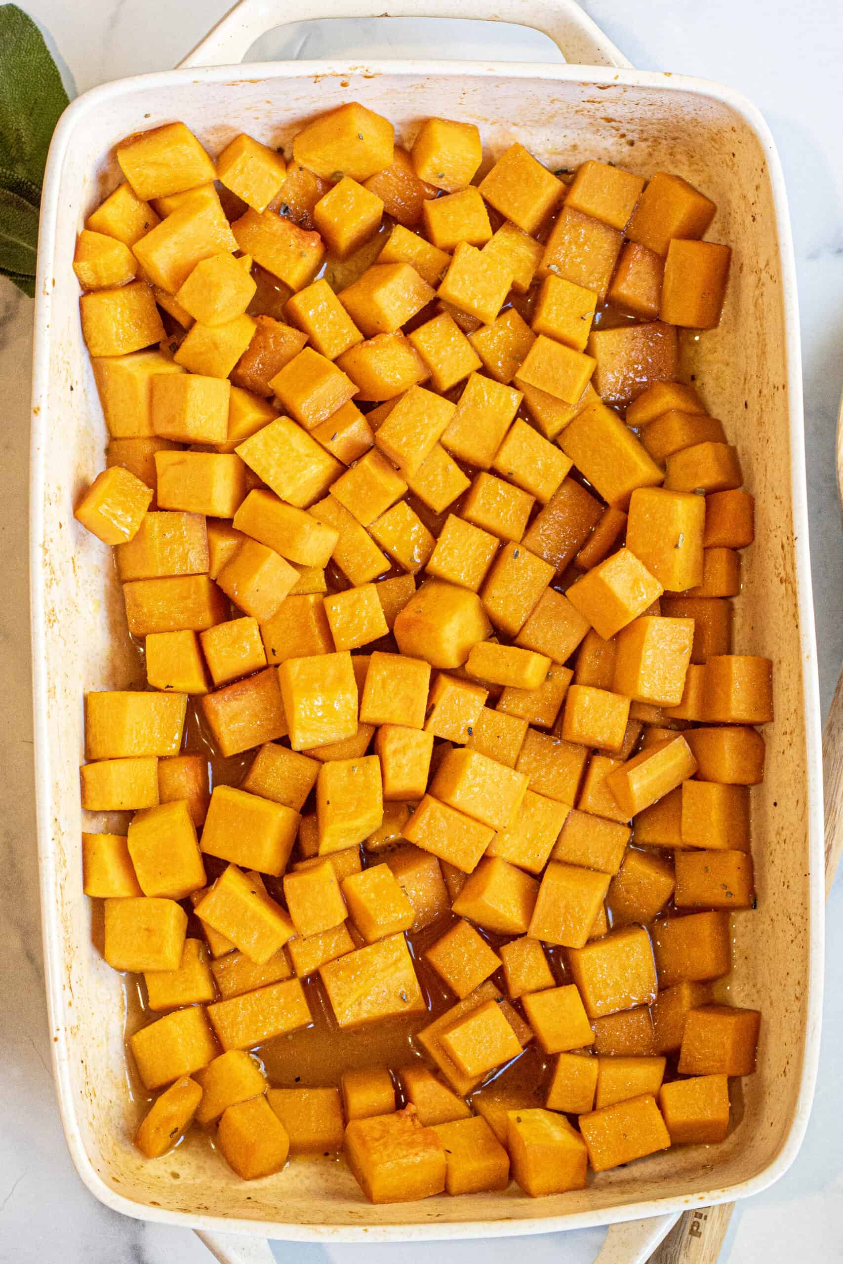 a roasting pan with cooked cubed butternut squash.