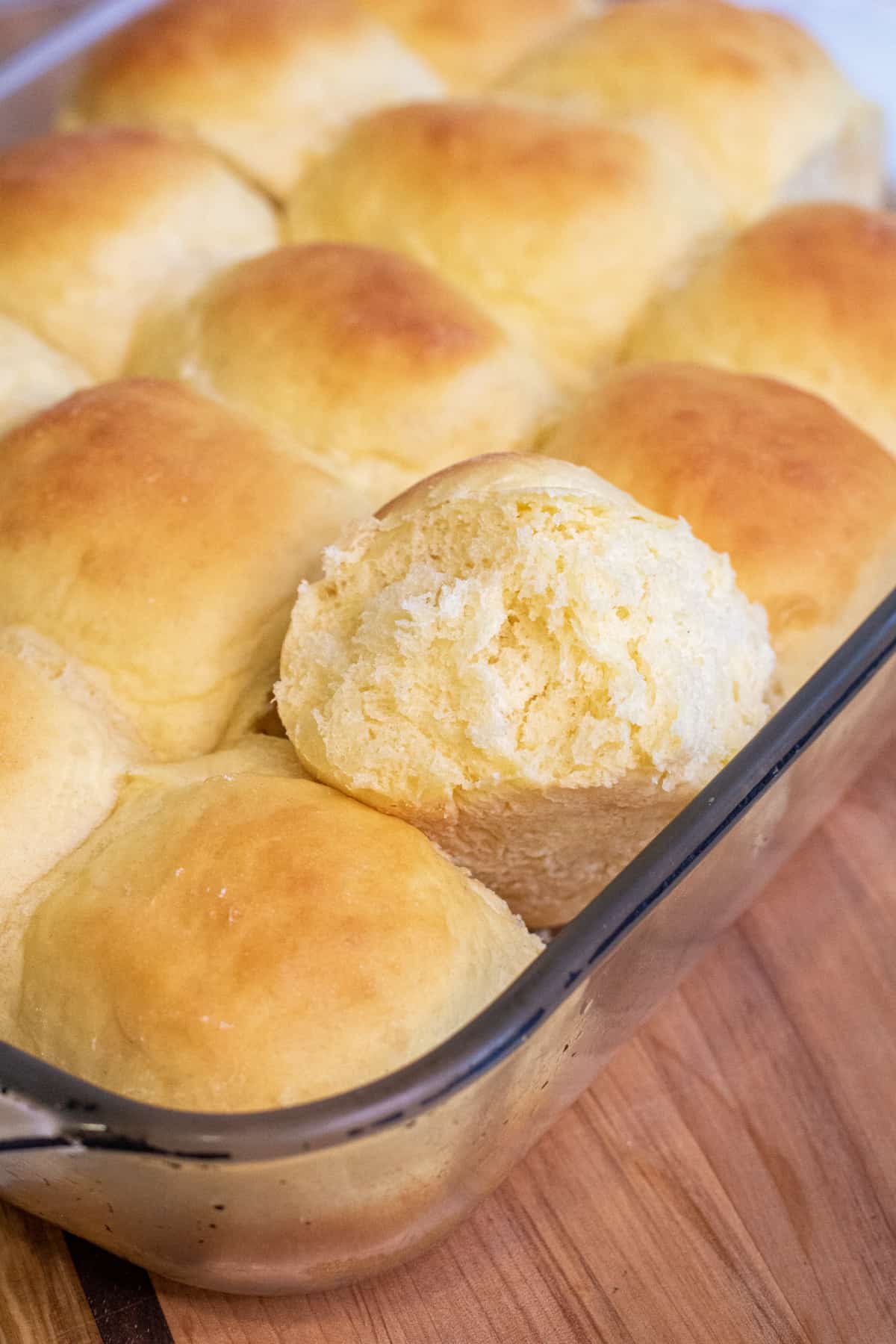 a tray of Hawaiian sweet dinner rolls with one roll out.