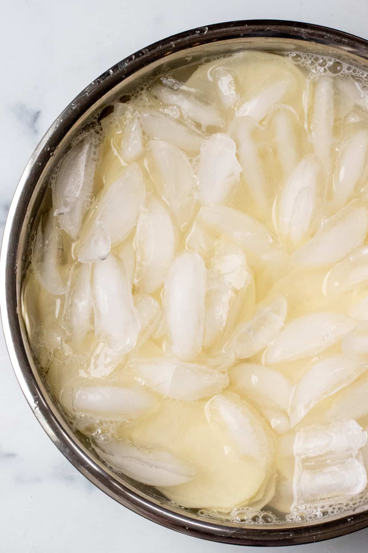 a bowl with a ice and sliced potatoes.