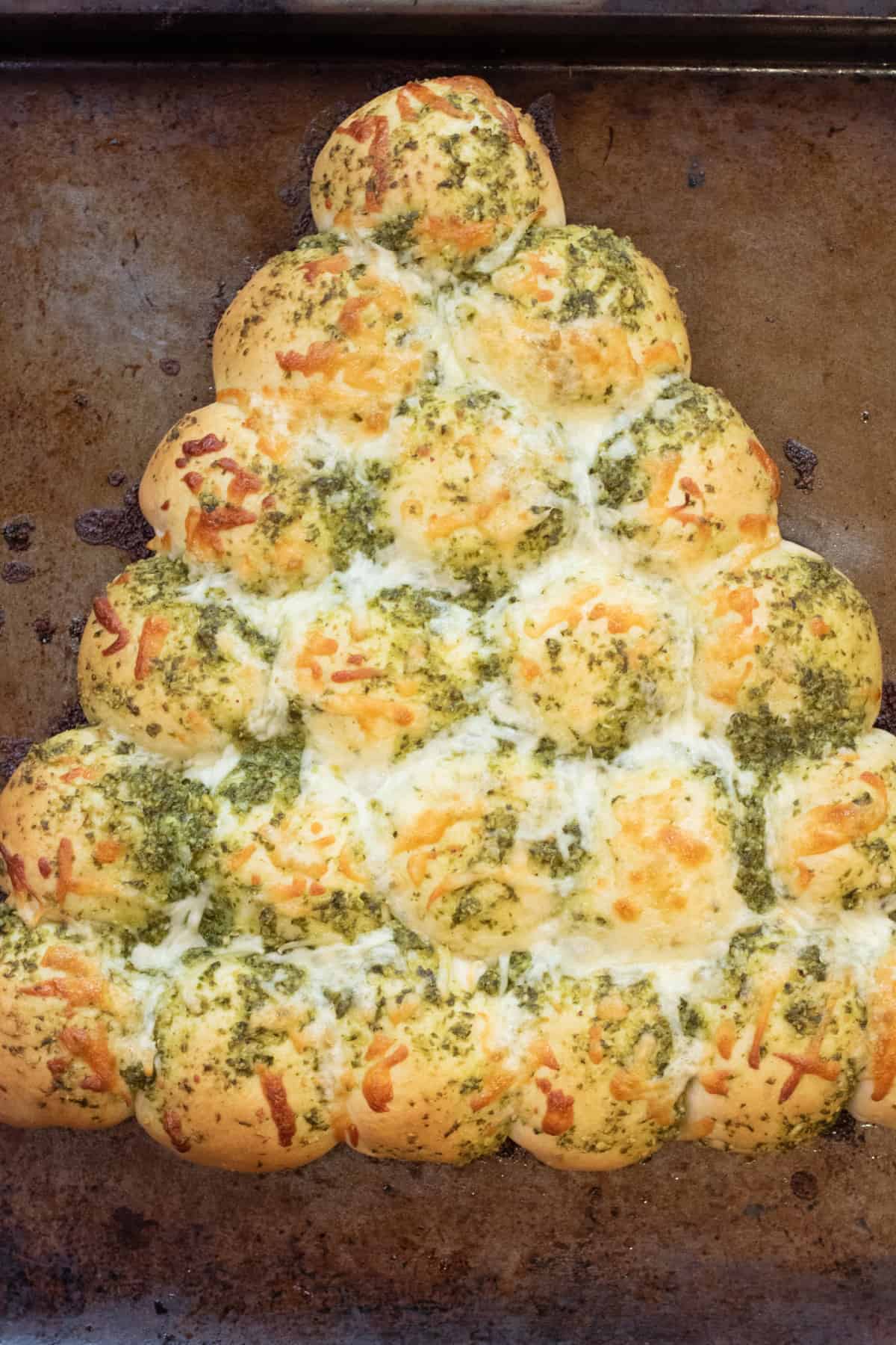 a baked Christmas tree shaped rolls with pesto and melted cheese.