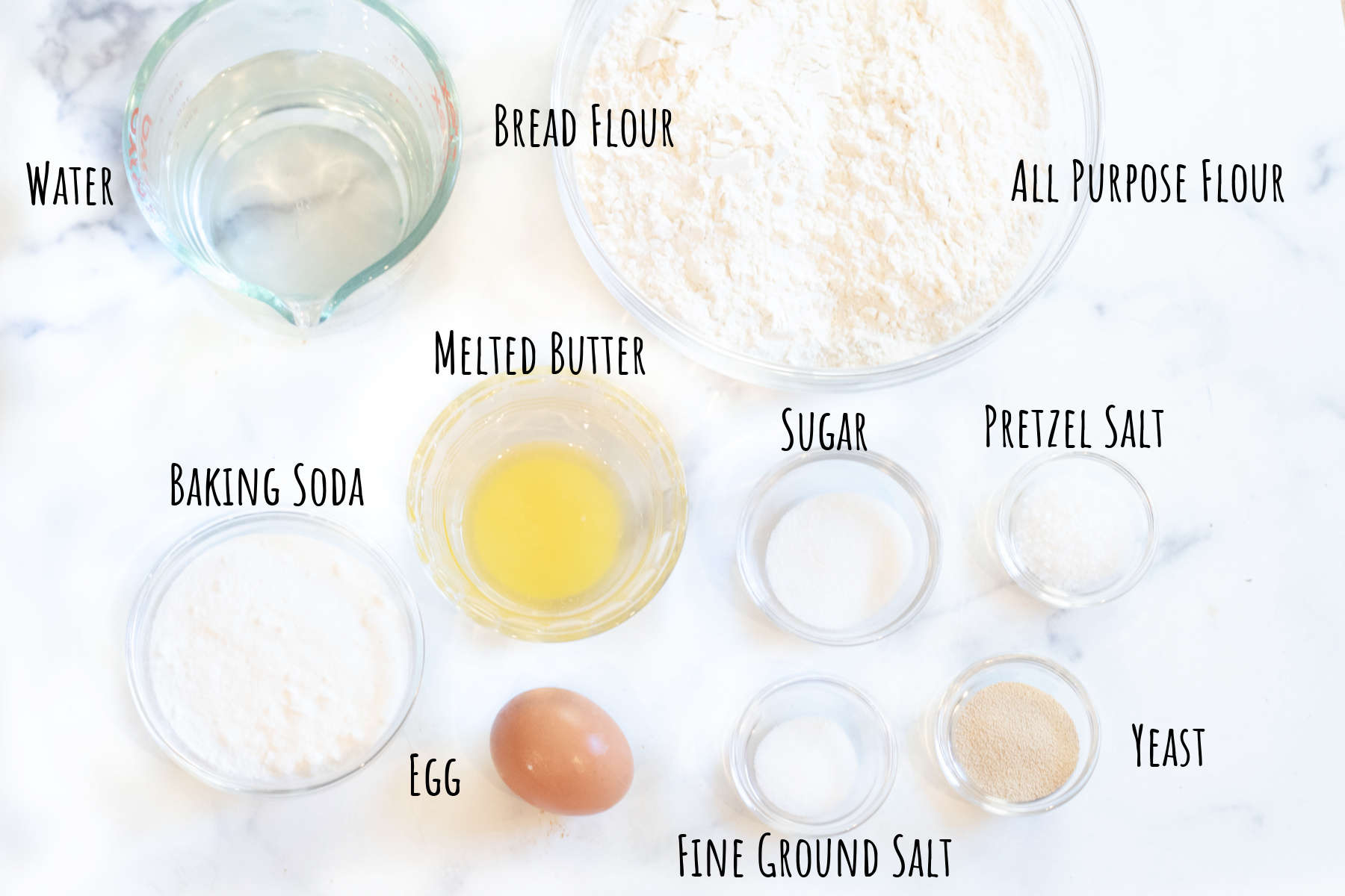 water, flour, melted butter, egg, sugar, baking soda, salts, yeast all in bowls and labeled.