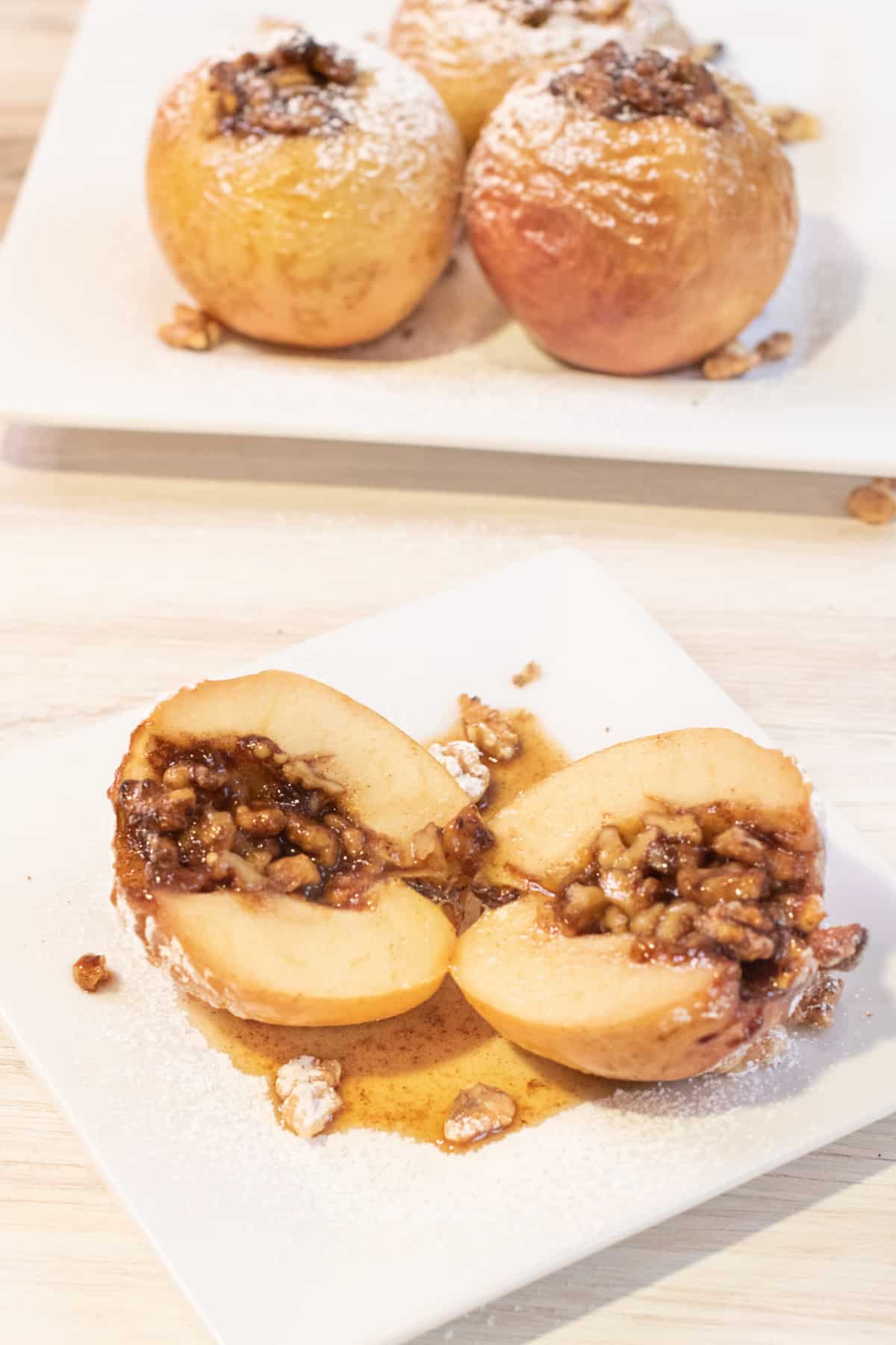 a halved baked apple with walnuts inside on a plate.