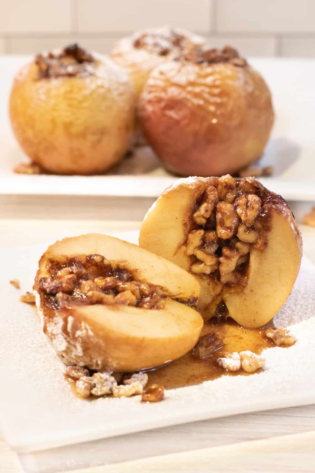 a halved baked apple with walnuts inside on a plate.