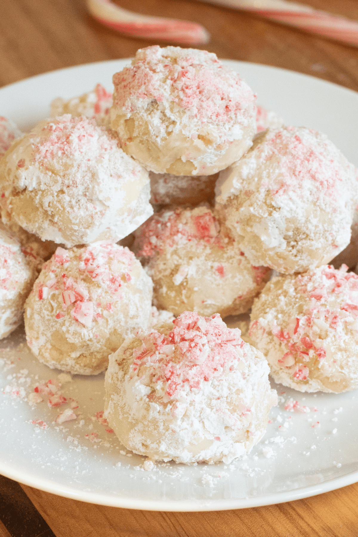 a plate of snowball cookies with crushed candy cane pieces.