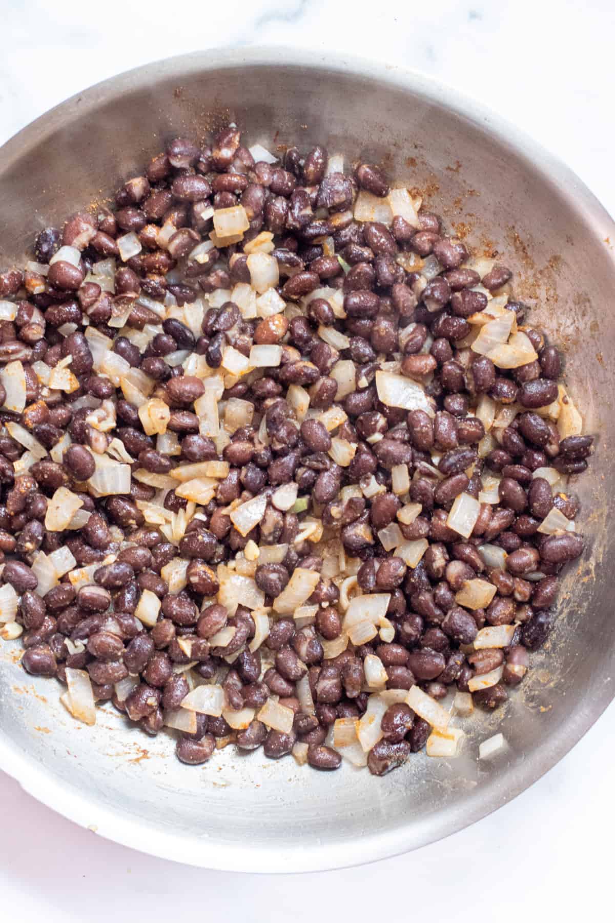 a pan of cooked black beans, onion, and garlic.