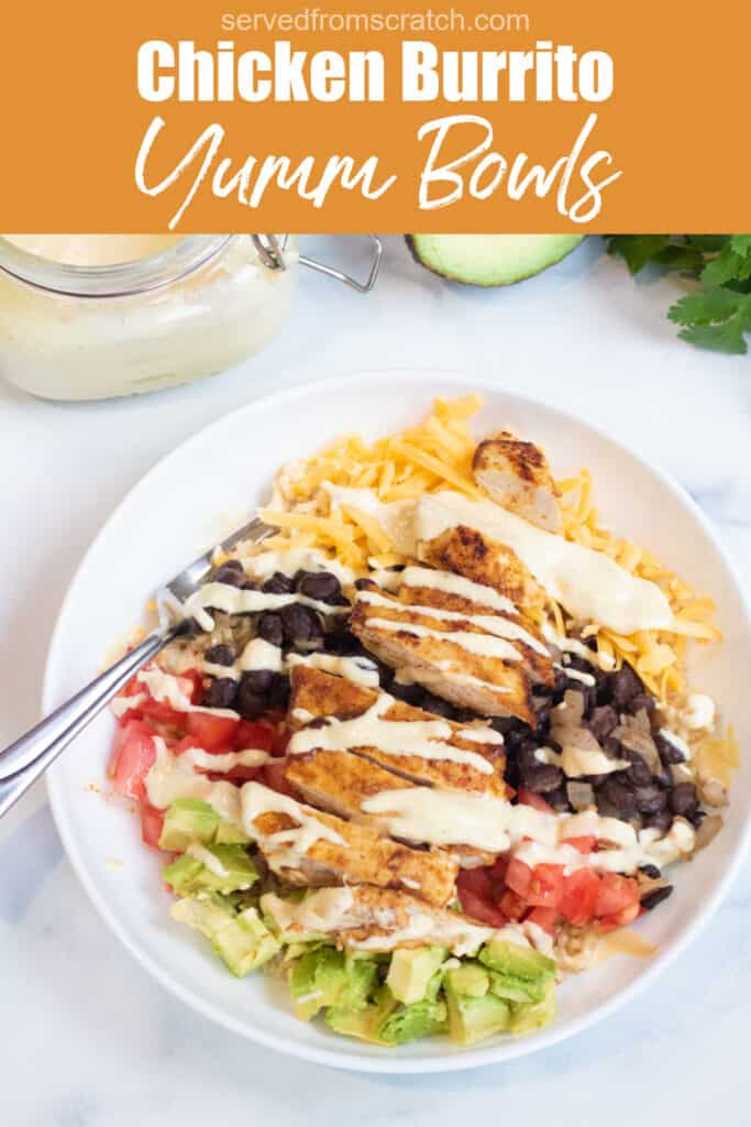 an overhead of a bowl of rice, cheese, avocado, tomatoes, black beans, chicken, and sauce with Pinterest pin text.