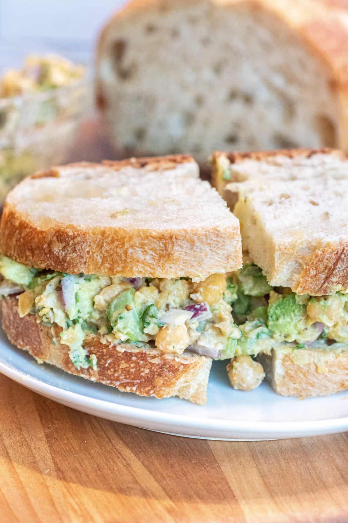 a sandwich of chickpea and avocado salad on a plate.