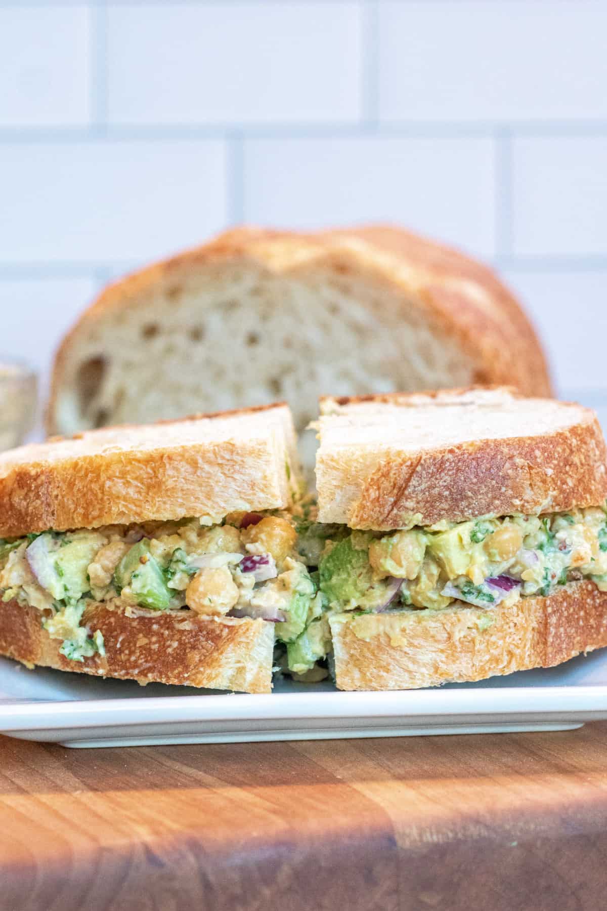 a sandwich of chickpea and avocado salad on a plate.