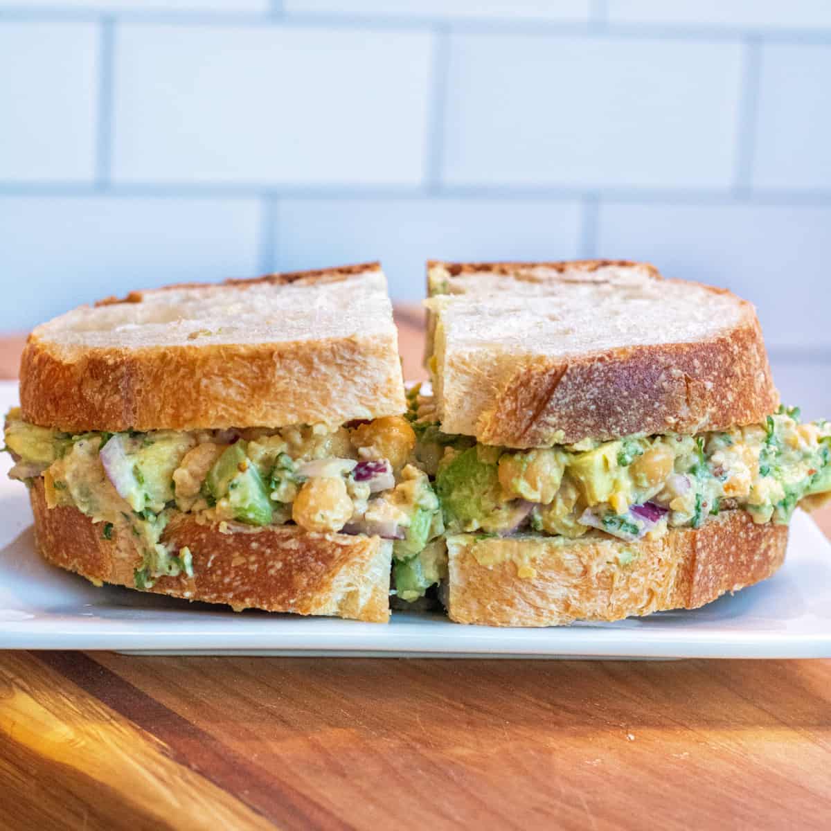 a sandwich of chickpea and avocado salad on a plate. 