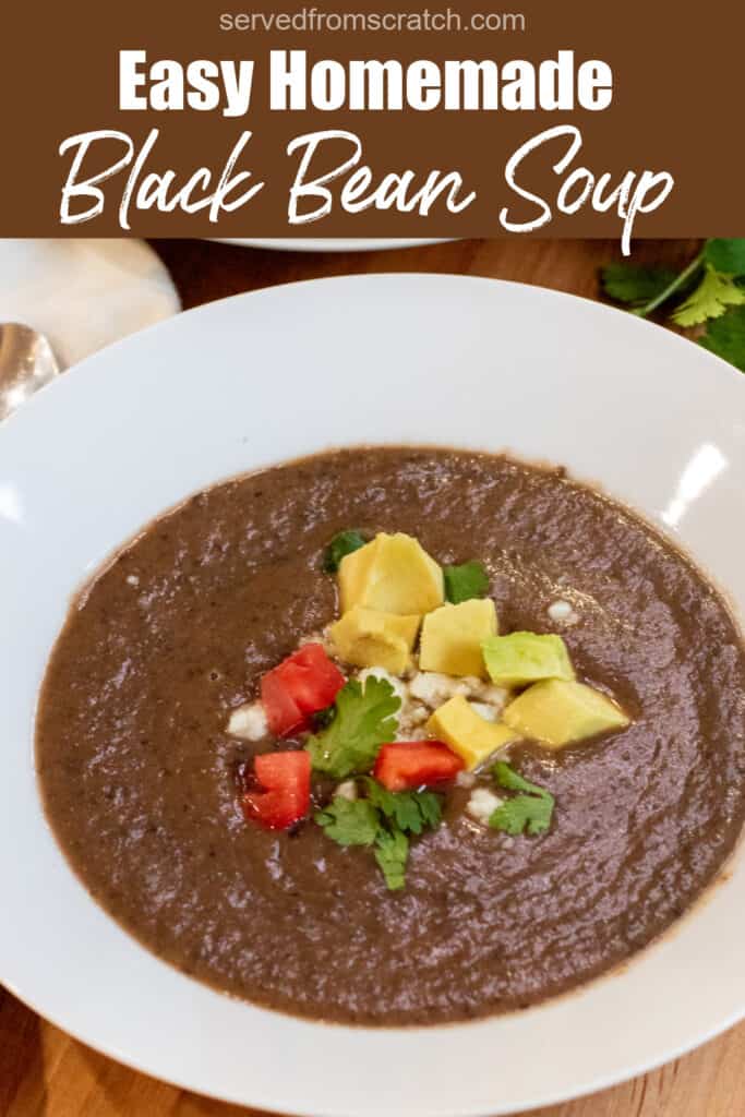 a bowl of black bean soup topped with avocado, cheese, and diced tomatoes with Pinterest pin text.