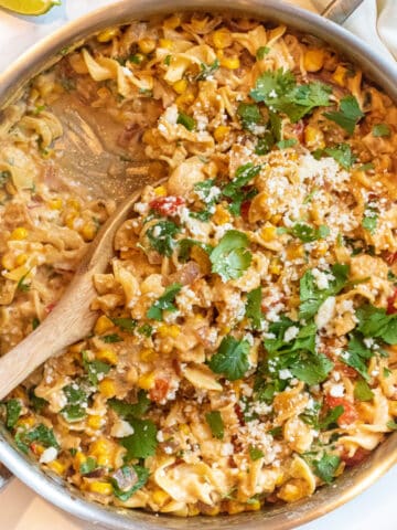 an overhead of a pan of pasta with cilantro, cheese, corn and a creamy sauce.