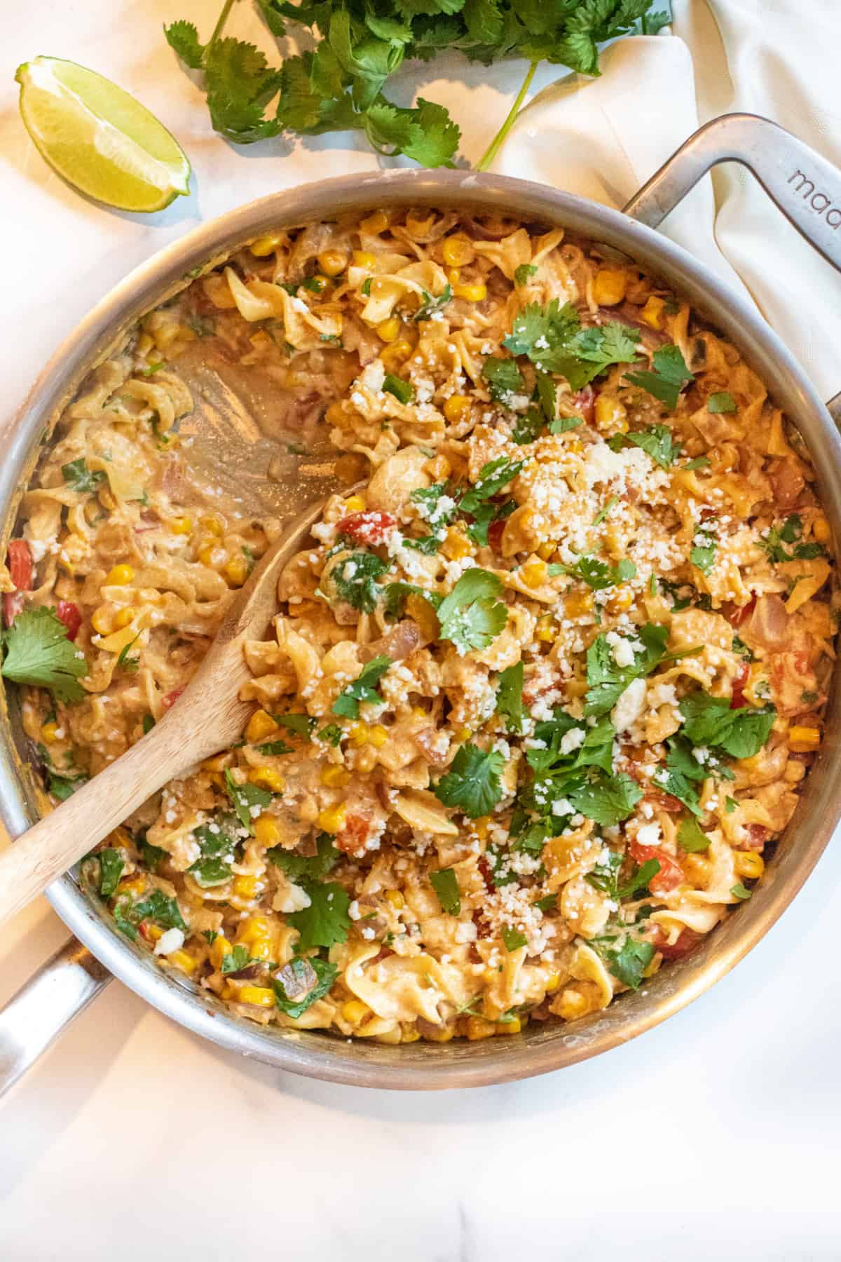an overhead of a pan of pasta with cilantro, cheese, corn and a creamy sauce.