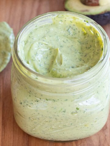 an open mason jar of a green creamy dressing.