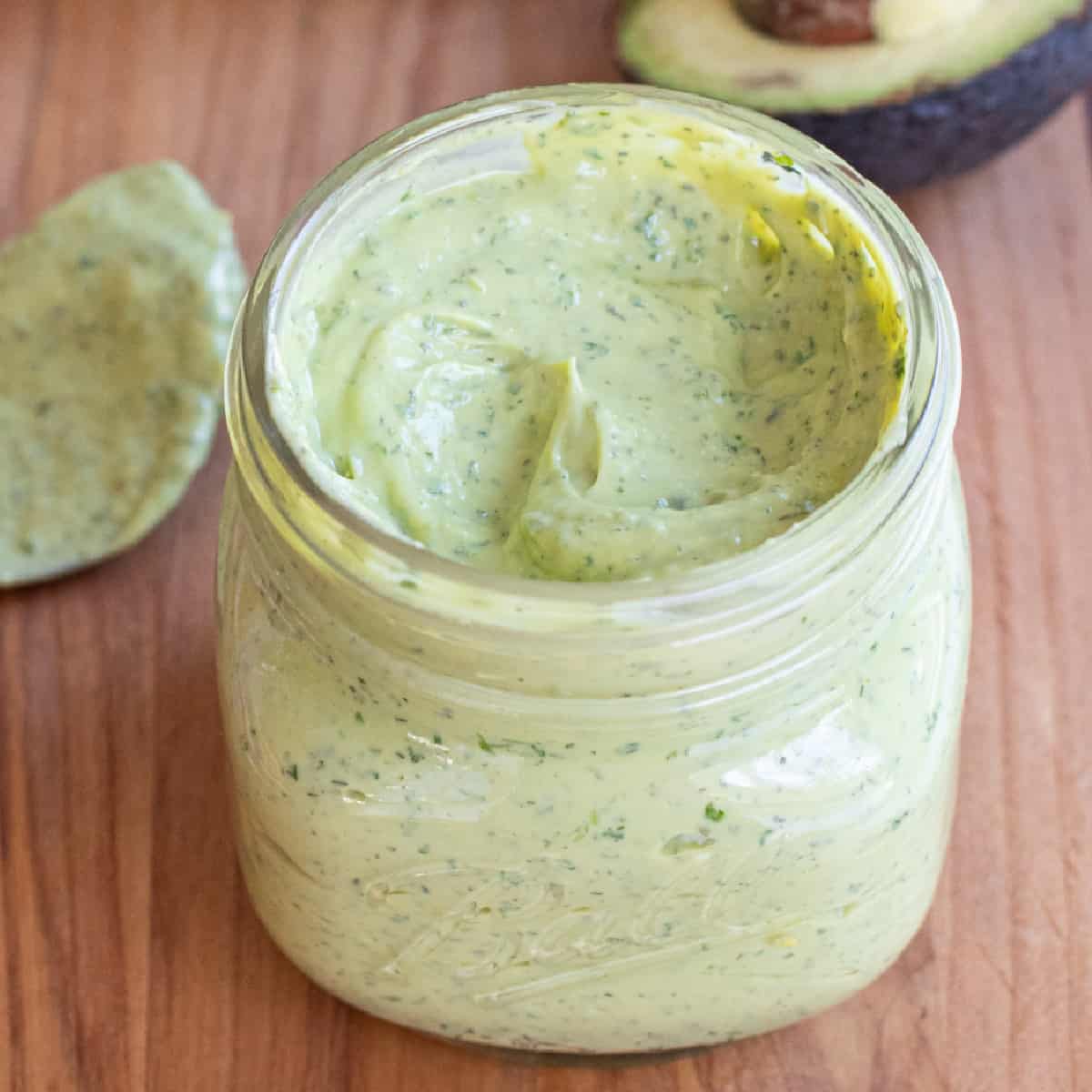 an open mason jar of a green creamy dressing.