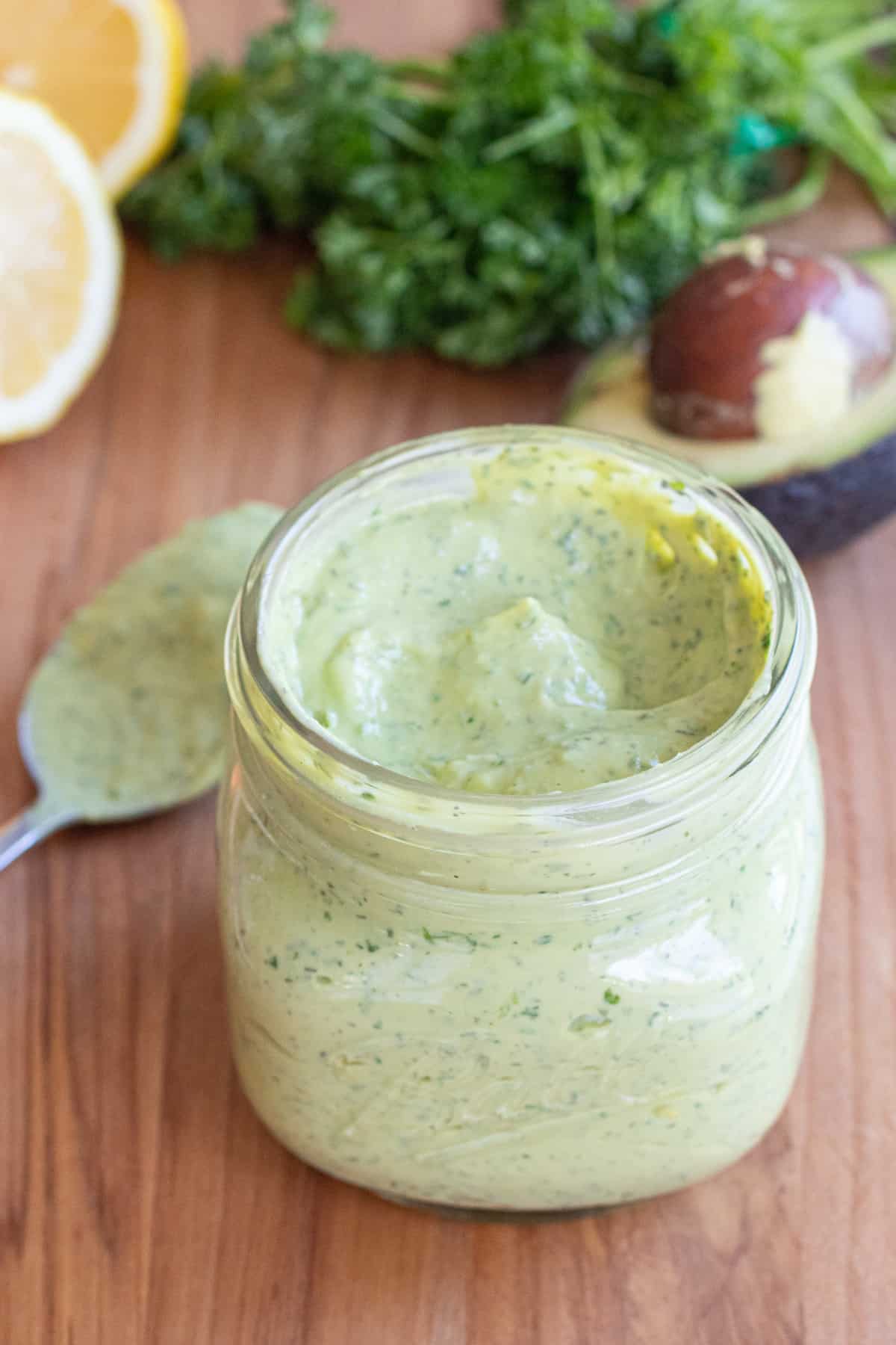 an open mason jar of a green creamy dressing.