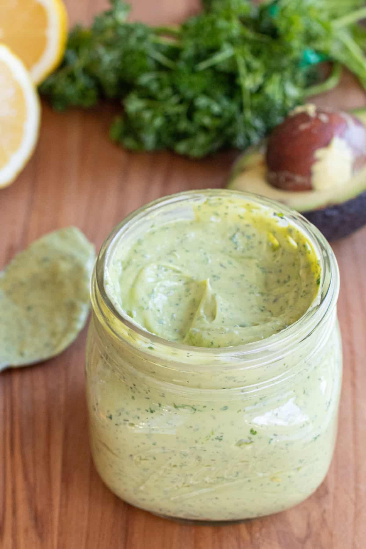 an open mason jar of a green creamy dressing.