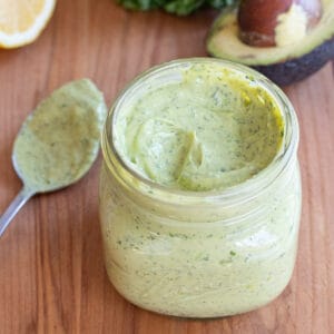 an open mason jar of a green creamy dressing.