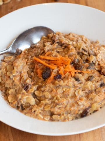 a bowl of carrot cake oatmeal with a spoon in it.