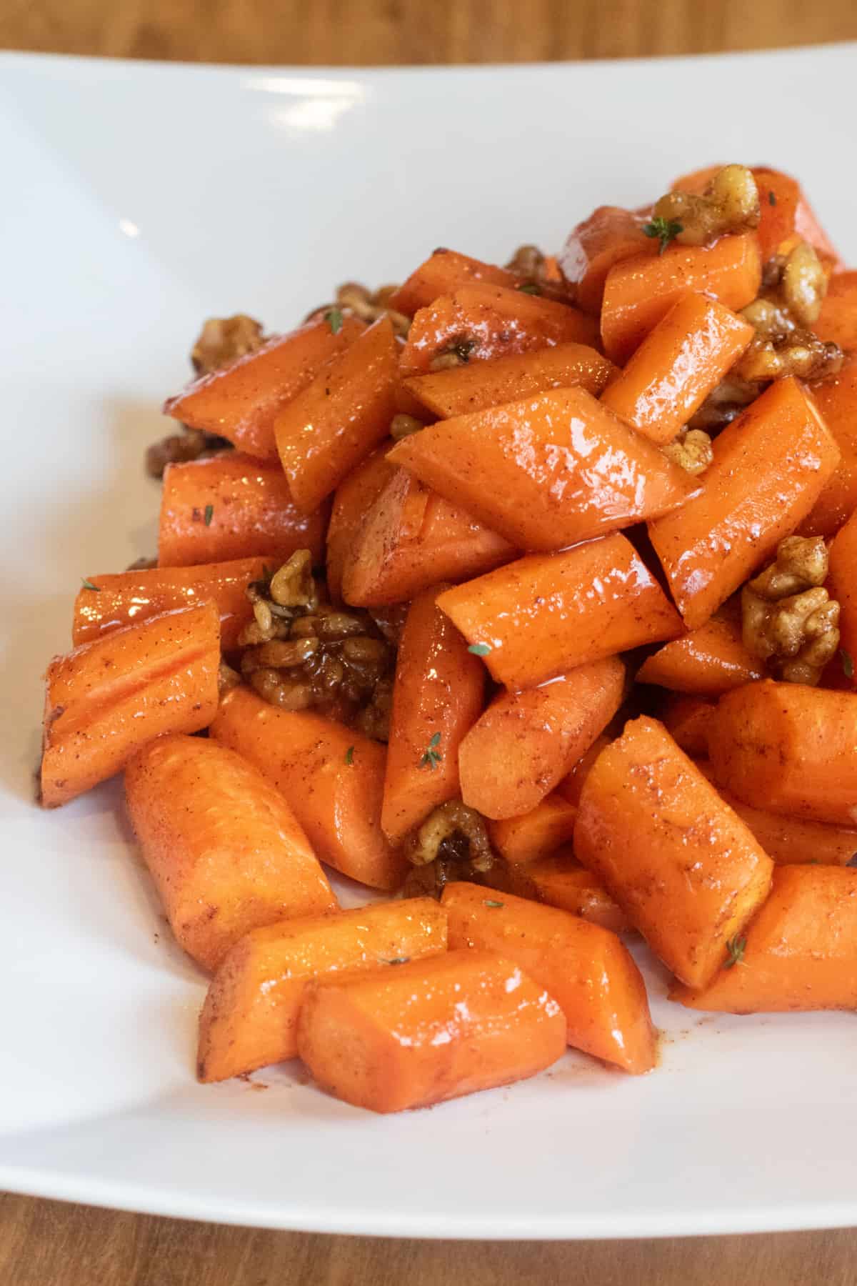 a plate of glazed carrots with walnuts.