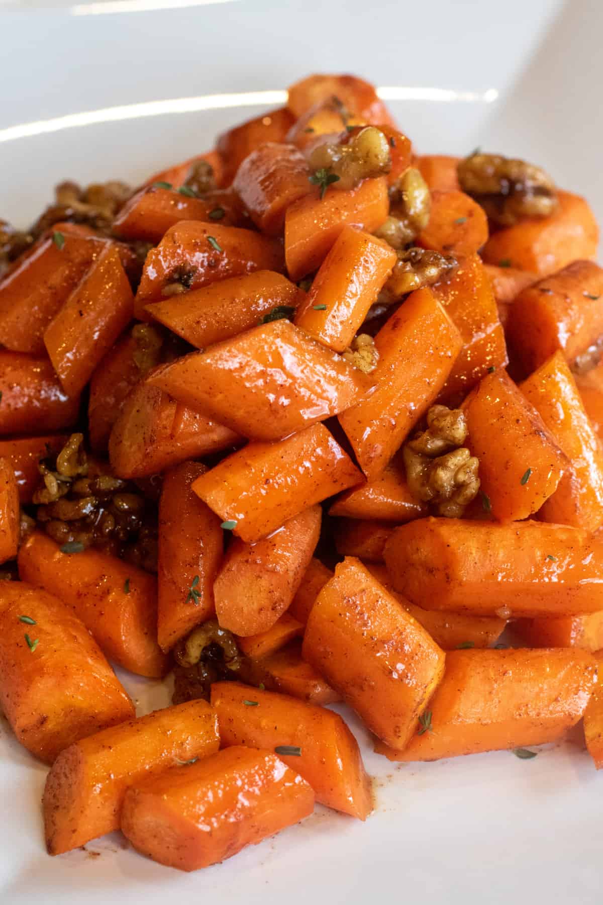 a plate of glazed carrots with walnuts.
