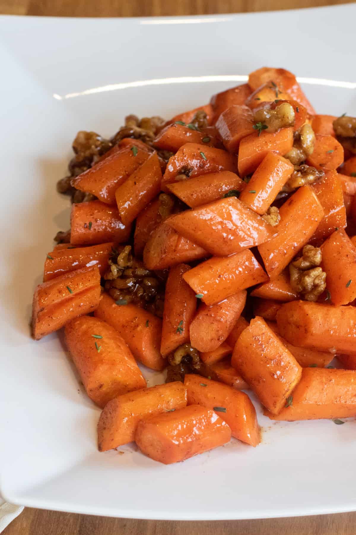 a plate of glazed carrots with walnuts.