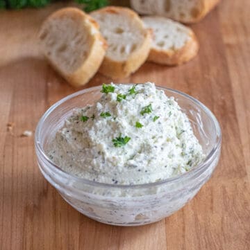 a bowl of whipped feta with sliced baguette behind it.