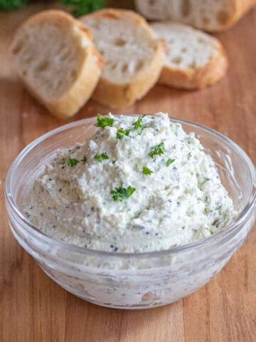 a bowl of whipped feta with sliced baguette behind it.