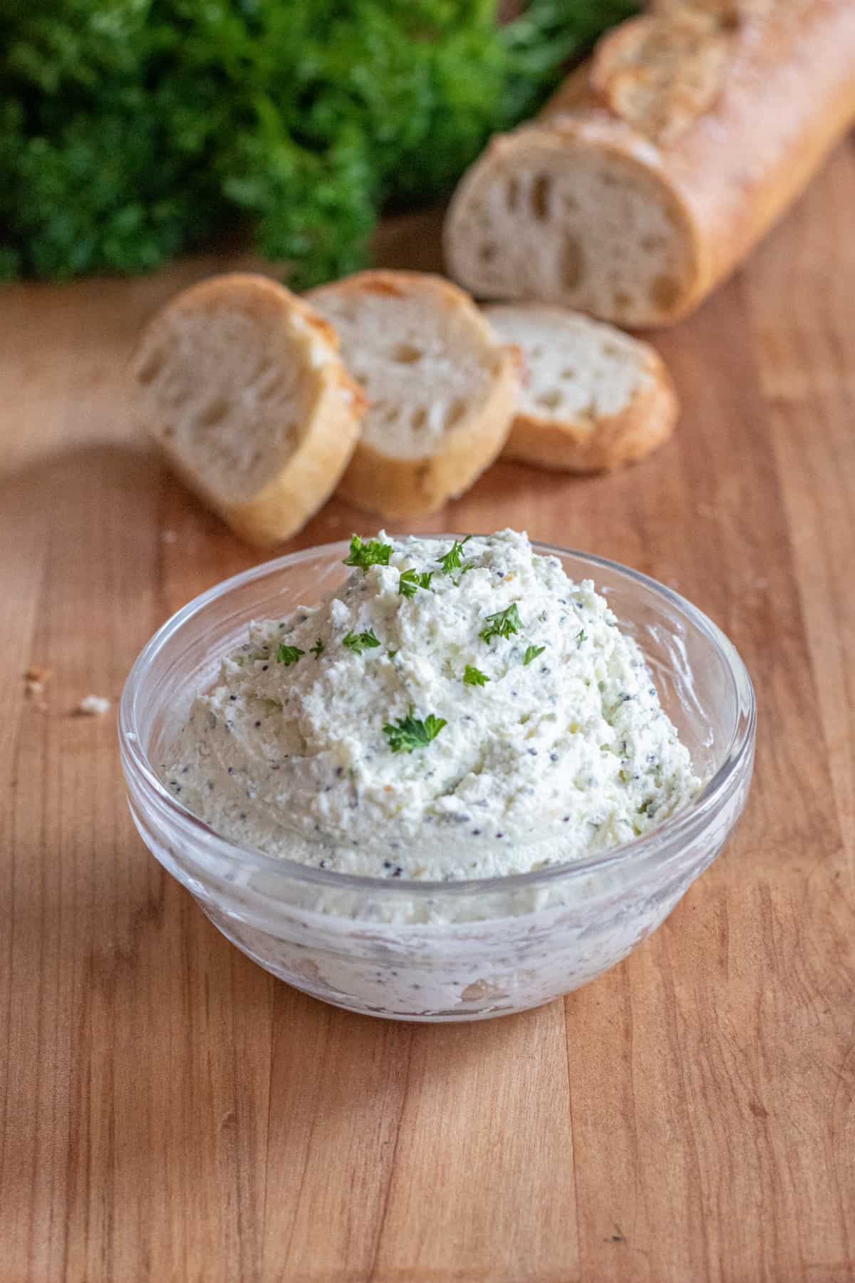 a bowl of whipped feta with sliced baguette behind it.