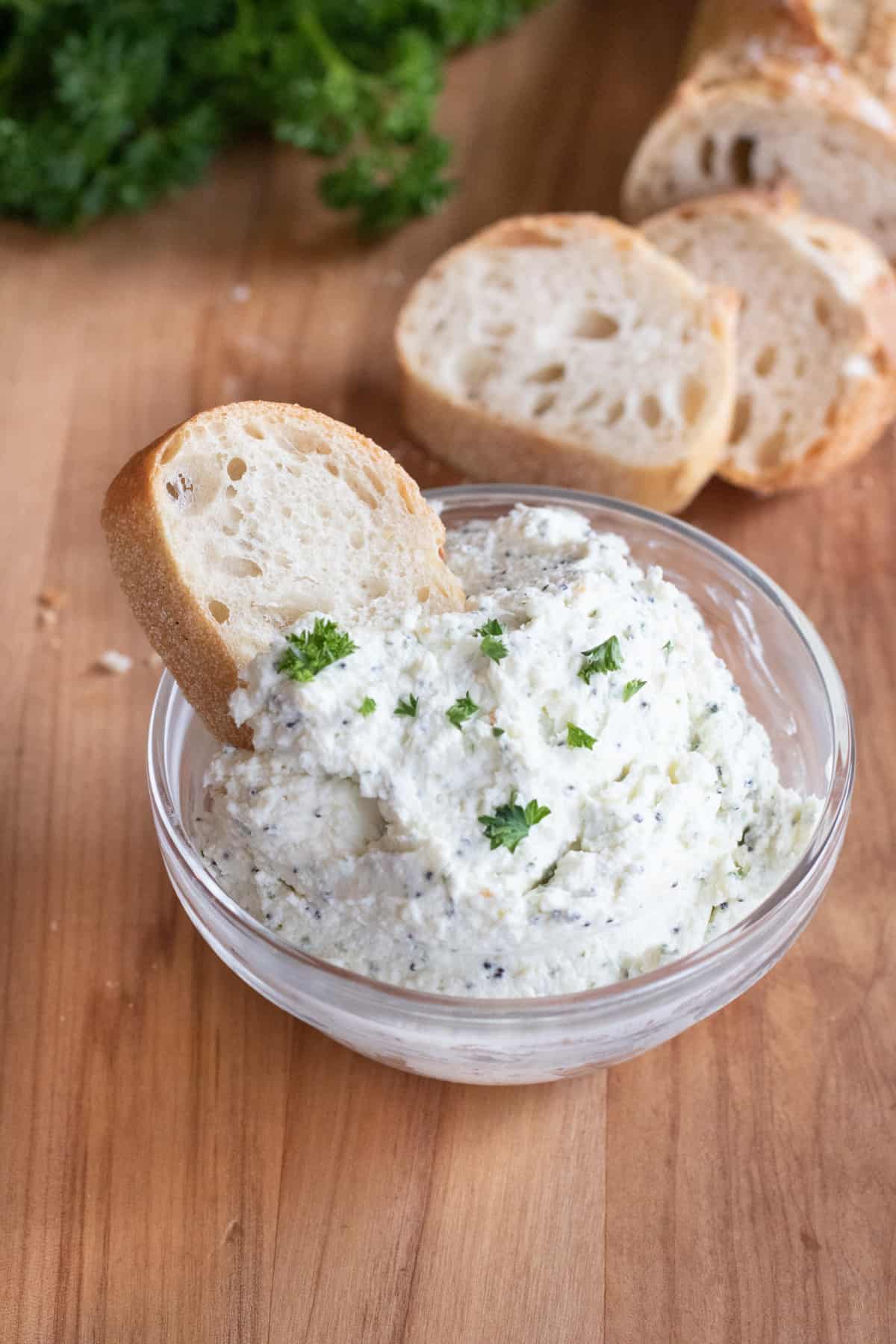a bowl of whipped feta with sliced baguette in it and behind it.