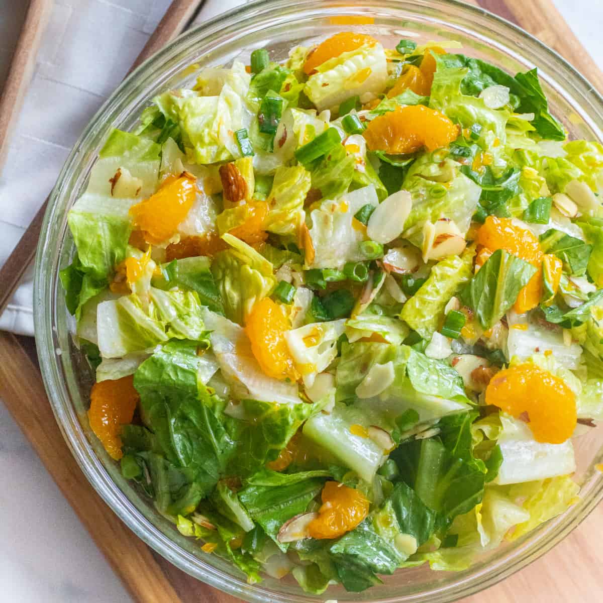 an overhead shot of a bowl of romaine lettuce salad with mandarins and almonds.