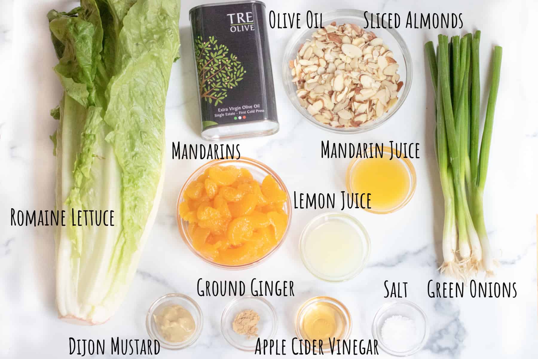 romaine lettuce, mandarins, almonds, green onions, olive oil, spices, almonds on a counter.