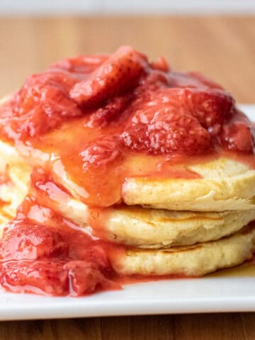 a stack of pancakes with strawberry compote on top.