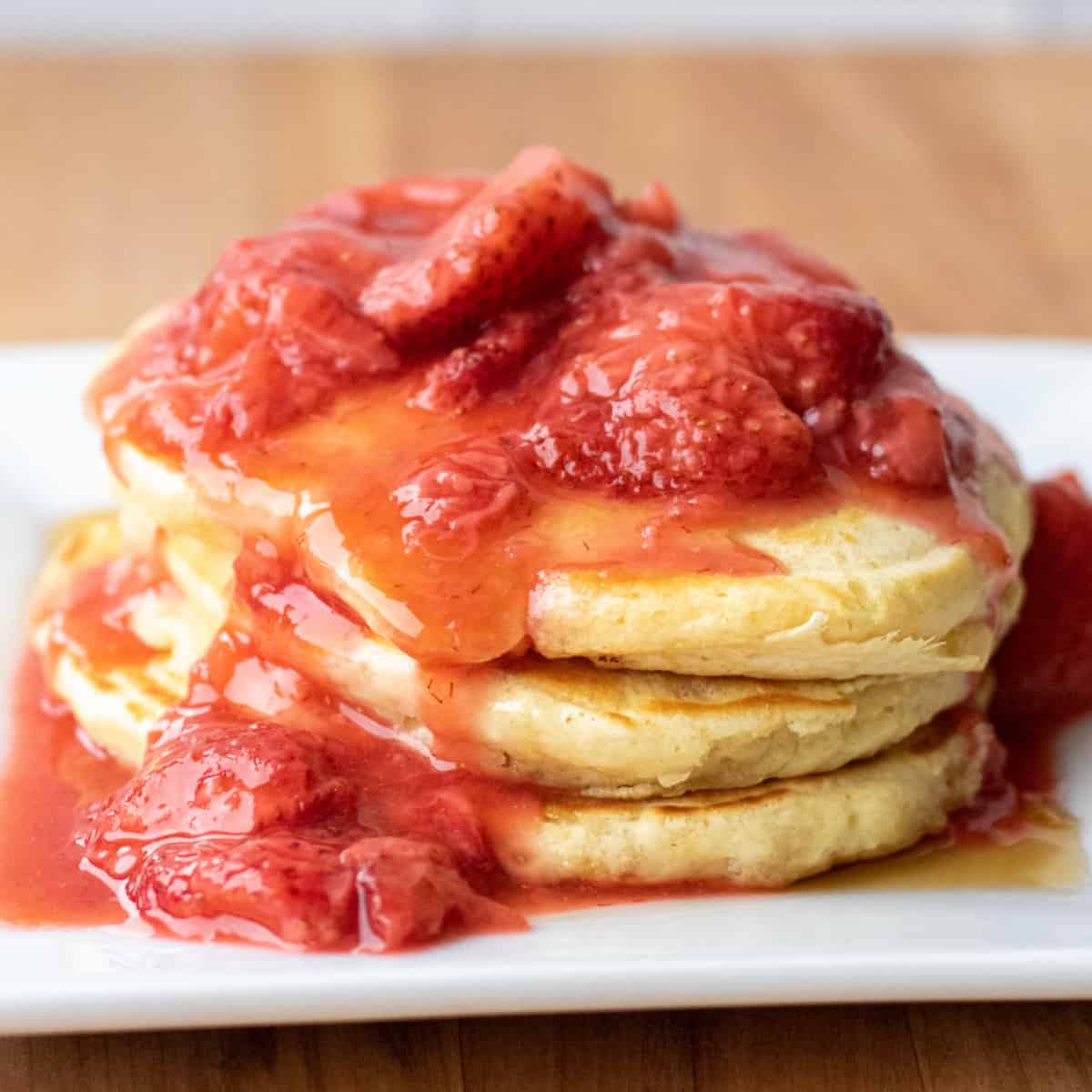 a stack of pancakes with strawberry compote on top.