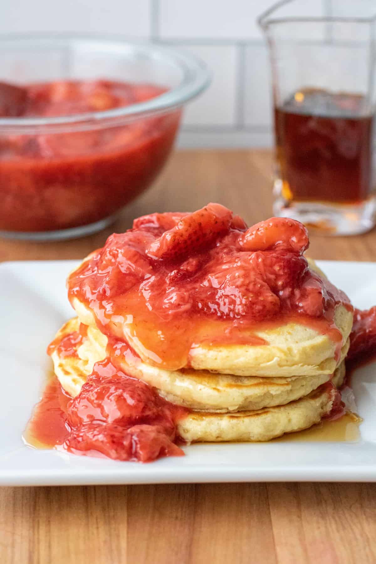 a stack of pancakes with strawberry compote on top.