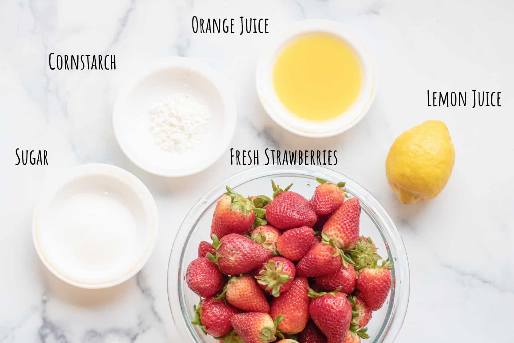 a bowl of fresh strawberries and bowls of juice, sugar, and cornstach and a lemon.