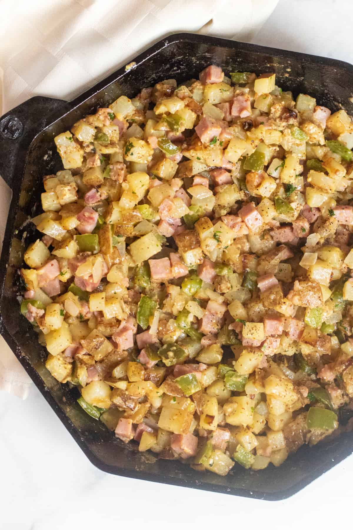 an overhead of a cast iron with diced potatoes and ham hash.