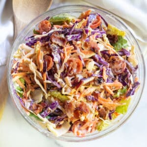 a bowl of coleslaw with bacon tomatoes and some lettuce.