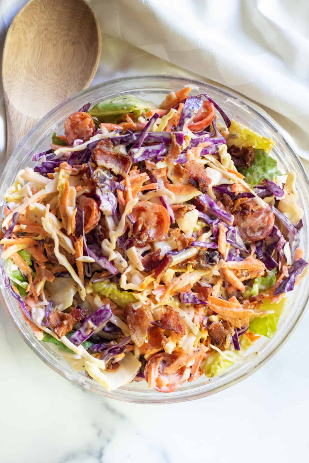 a bowl of coleslaw with bacon tomatoes and some lettuce.