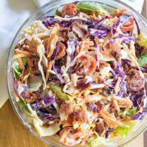 a bowl of coleslaw with bacon tomatoes and some lettuce.