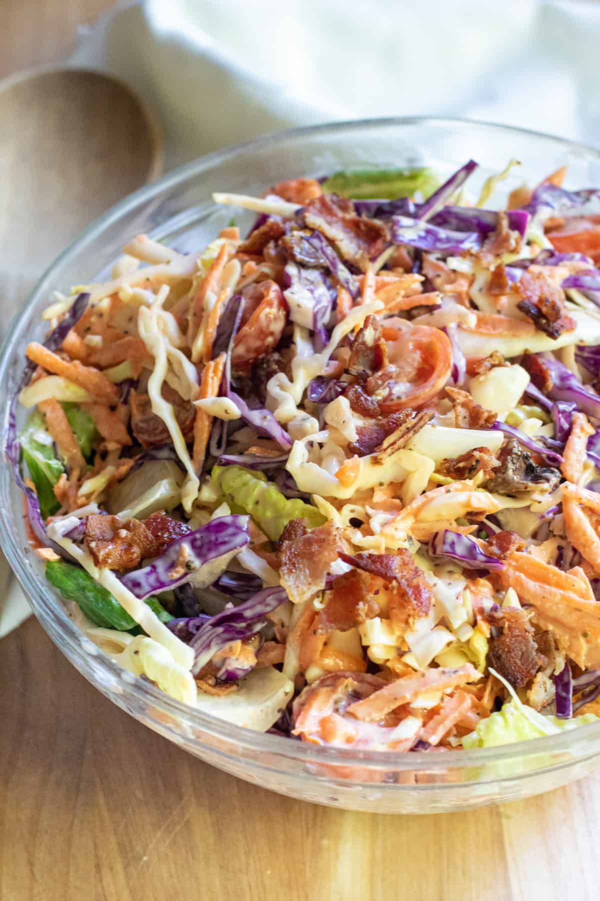 a bowl of coleslaw with bacon tomatoes and some lettuce.