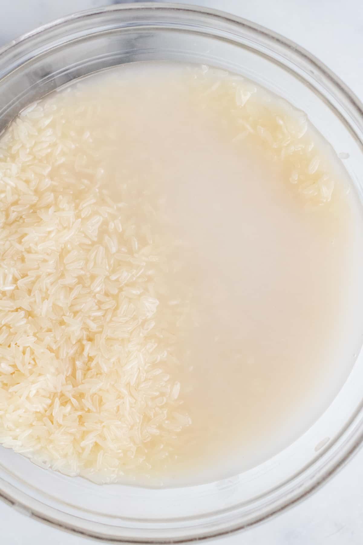 a bowl of uncooked rice in murky water.