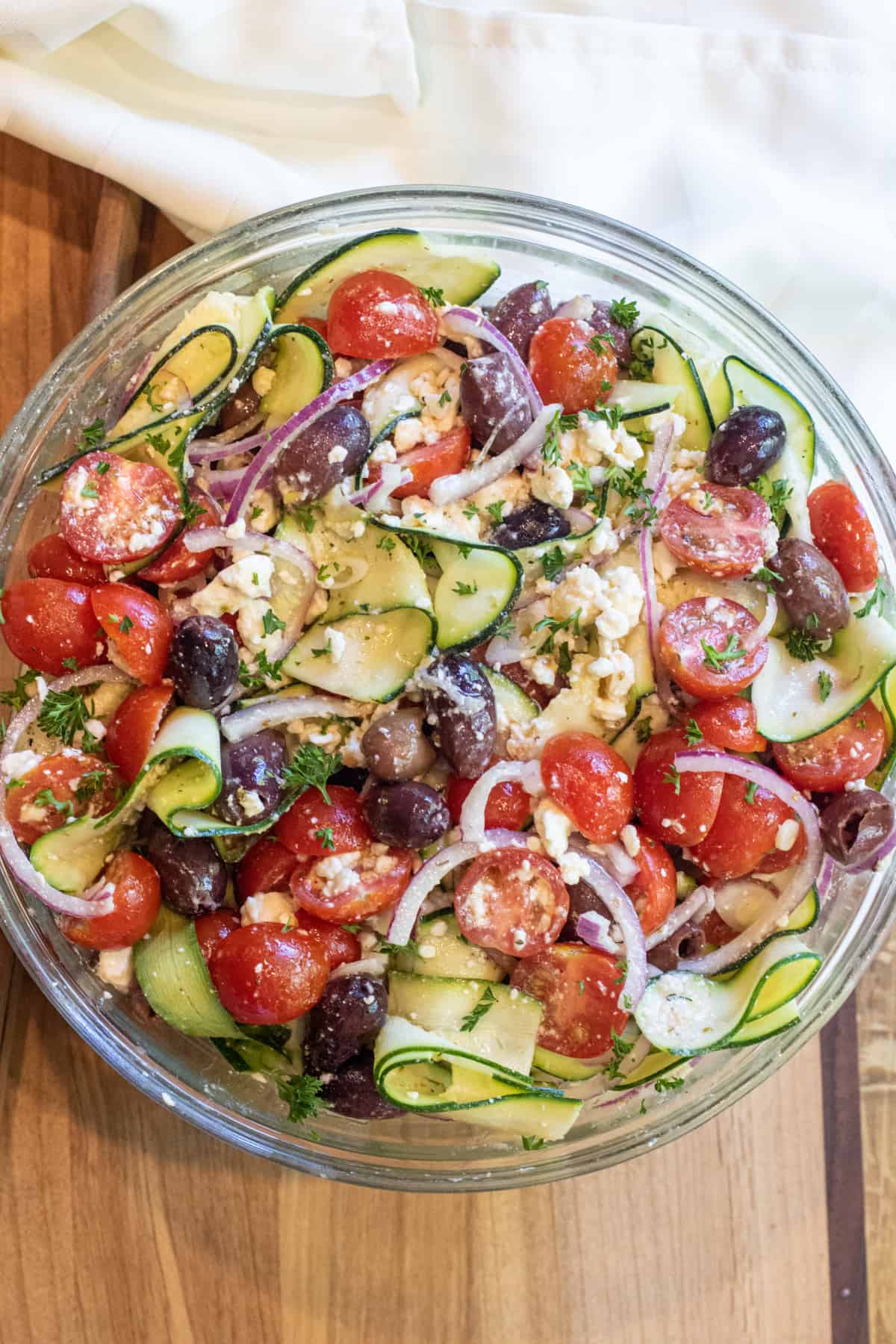 a bowl of zucchini salad with tomatoes, olives, onions and feta.