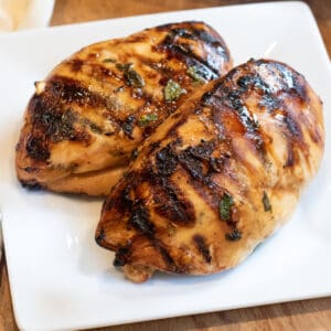 two grilled chicken breasts on a plate.